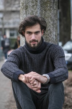 Yakışıklı İtalyan siyah saçlı çocuk alçak duvarda oturuyor. Yüksek kalite fotoğraf