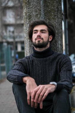 Yakışıklı İtalyan siyah saçlı çocuk alçak duvarda oturuyor. Yüksek kalite fotoğraf