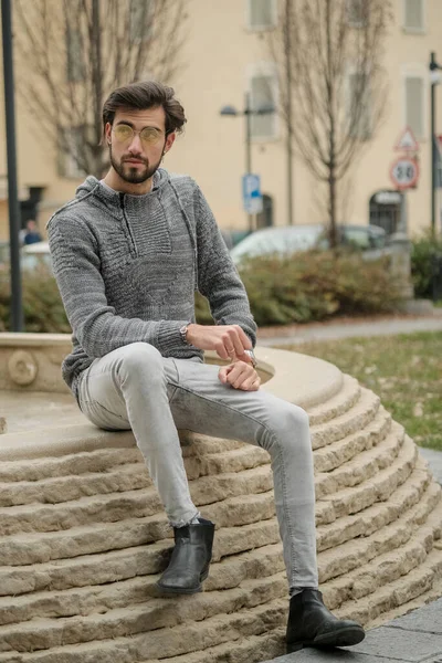 Yakışıklı, siyah saçlı İtalyan çocuk anıtın üzerinde oturuyor. Yüksek kalite fotoğraf