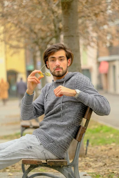 Bankta oturan koyu renk tişörtlü yakışıklı İtalyan çocuk. Yüksek kalite fotoğraf