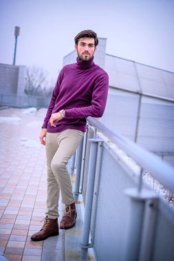 Terasta metal korkuluklara yaslanmış yakışıklı siyah saçlı çocuk. Yüksek kalite fotoğraf