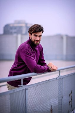 Terasta metal korkuluklara yaslanmış yakışıklı siyah saçlı çocuk. Yüksek kalite fotoğraf