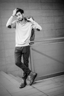 Yakışıklı, siyah saçlı, metal korkuluklara yaslanmış bir çocuk. Yüksek kalite fotoğraf