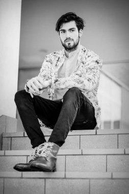 Beyaz merdivenlerde oturan yakışıklı, siyah saçlı İtalyan adam. Yüksek kalite fotoğraf