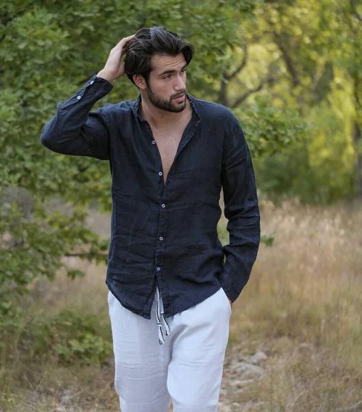 Kuru çimenlerde gömleği olan yakışıklı, siyah saçlı bir İtalyan. Yüksek kalite fotoğraf