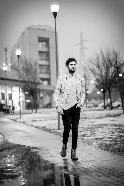 handsome dark-haired italian guy walk in snowy winter park at evening. High quality photo