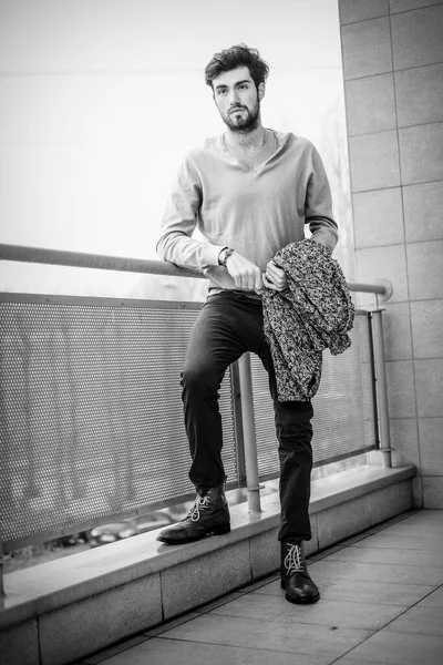 Yakışıklı, siyah saçlı, metal korkuluklara yaslanmış bir çocuk. Yüksek kalite fotoğraf