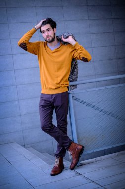 Yakışıklı, siyah saçlı, metal korkuluklara yaslanmış bir çocuk. Yüksek kalite fotoğraf