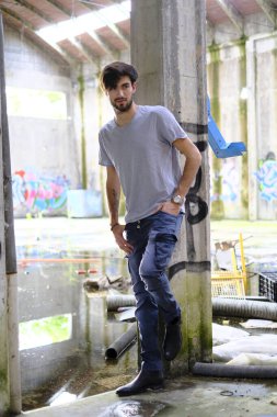 Dejenere olmuş terk edilmiş fabrikadaki yakışıklı siyah saçlı İtalyan adam. Yüksek kalite fotoğraf