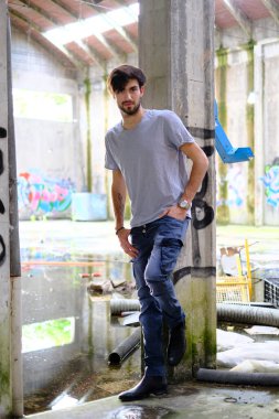 Dejenere olmuş terk edilmiş fabrikadaki yakışıklı siyah saçlı İtalyan adam. Yüksek kalite fotoğraf