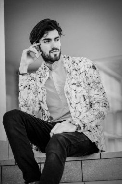 Beyaz merdivenlerde oturan yakışıklı, siyah saçlı İtalyan adam. Yüksek kalite fotoğraf