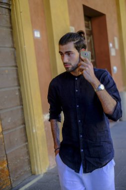 Ortadaki yakışıklı, siyah saçlı adam telefonu kullanıyor. Yüksek kalite fotoğraf