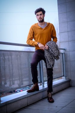 Yakışıklı, siyah saçlı, metal korkuluklara yaslanmış bir çocuk. Yüksek kalite fotoğraf