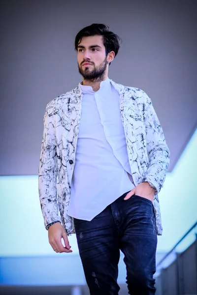 Yakışıklı, siyah saçlı, beyaz ceketli, merdivenlerde oturan adam. Yüksek kalite fotoğraf