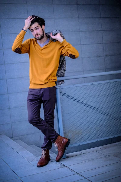 Yakışıklı, siyah saçlı, metal korkuluklara yaslanmış bir çocuk. Yüksek kalite fotoğraf