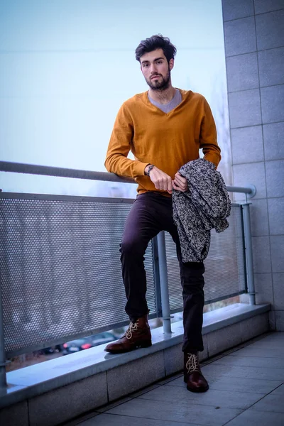 Uzun bir binanın çatısındaki yakışıklı, siyah saçlı adam. Yüksek kalite fotoğraf