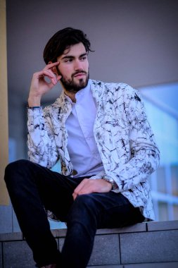 Beyaz merdivenlerde oturan yakışıklı, siyah saçlı İtalyan adam. Yüksek kalite fotoğraf