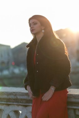 beautiful girl standing in red dress in city center. High quality photo