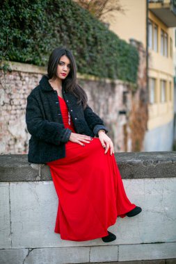 beautiful girl standing in red dress in city center. High quality photo