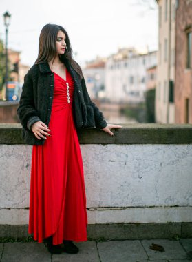 beautiful girl standing in red dress in city center. High quality photo