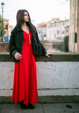 beautiful girl standing in red dress in city center. High quality photo