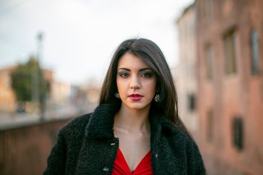 beautiful girl standing in red dress in city center. High quality photo