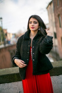 beautiful girl standing in red dress in city center. High quality photo