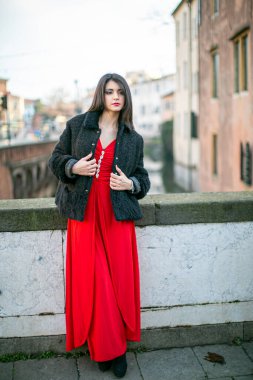 beautiful girl standing in red dress in city center. High quality photo