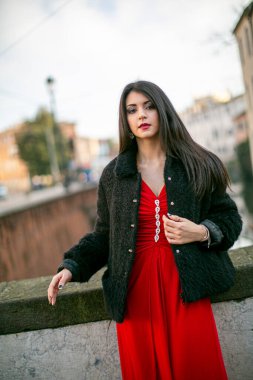 beautiful girl standing in red dress in city center. High quality photo
