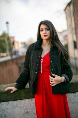 beautiful girl standing in red dress in city center. High quality photo