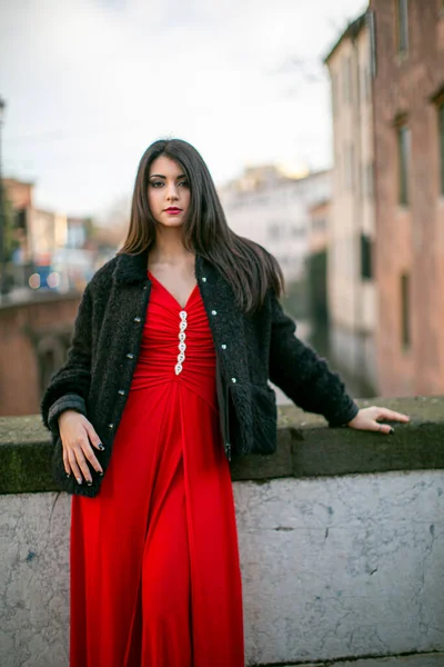 beautiful girl standing in red dress in city center. High quality photo