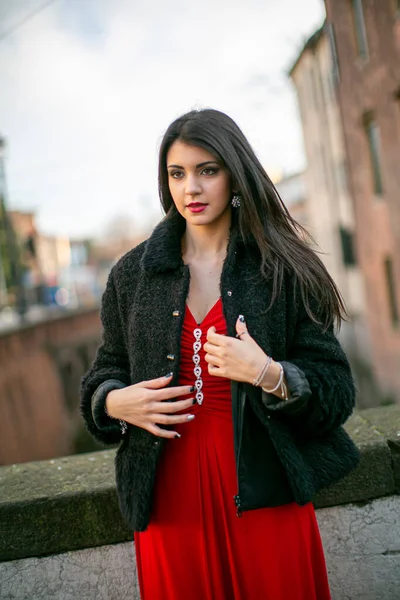 beautiful girl standing in red dress in city center. High quality photo