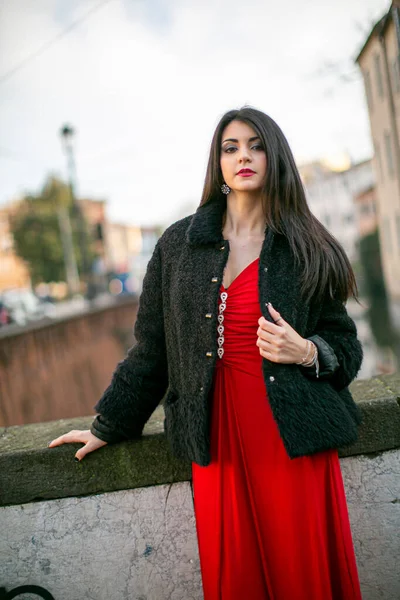 beautiful girl standing in red dress in city center. High quality photo