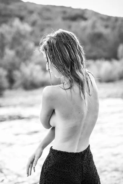 beautiful girl with open back posing on the bank of a river. High quality photo