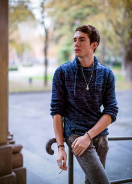 handsome guy with sweater smokes in the city center. High quality photo