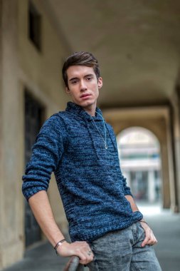 handsome guy with sweater smokes in the city center. High quality photo