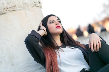beautiful brunette girl sitting under marble column. High quality photo