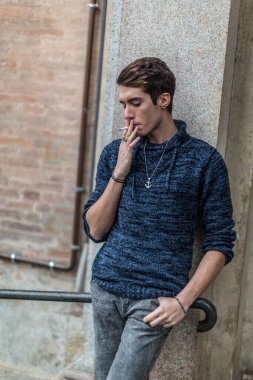handsome guy with sweater smokes in the city center. High quality photo