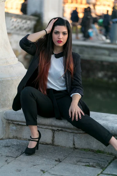 beautiful brunette girl sitting under marble column. High quality photo