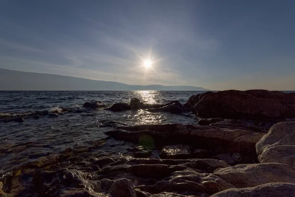 sunset on Lake Garda with rocks and waves. High quality photo