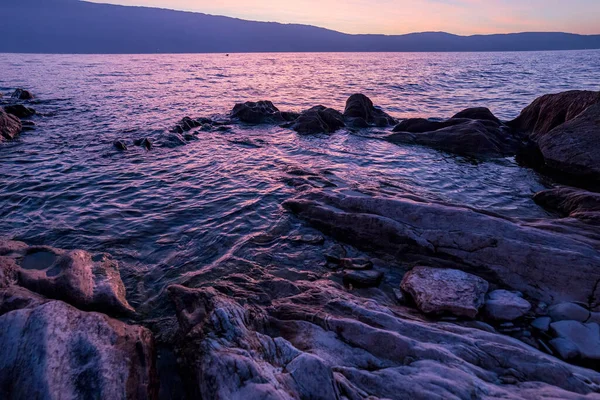 rocks in the lake at sunset sunrise on garda lake. High quality photo