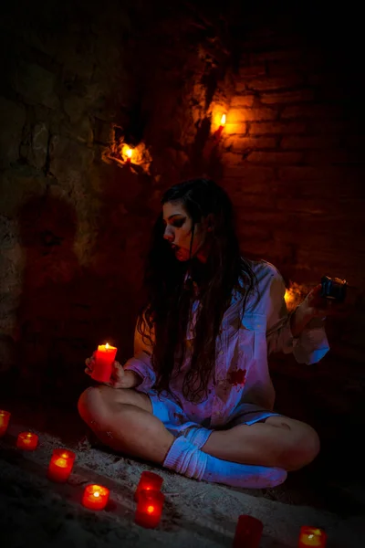 vampire dark goth girl with burning candles in a horror atmosphere. High quality photo