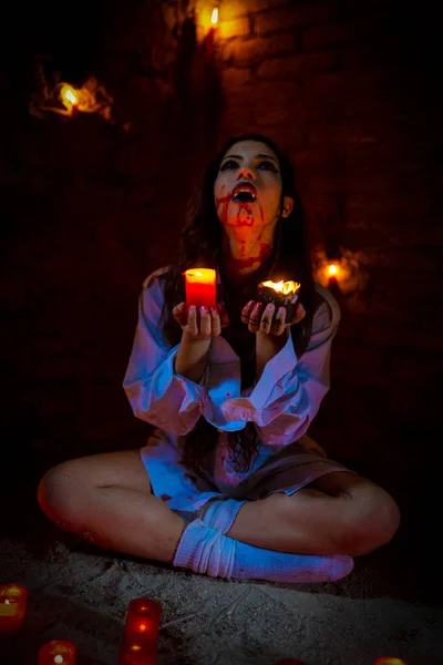 vampire dark goth girl with burning candles in a horror atmosphere. High quality photo