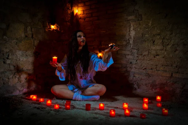 vampire dark goth girl with burning candles in a horror atmosphere. High quality photo