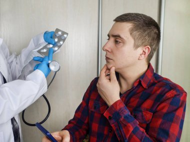 Klinikteki doktor bir adamı muayene ediyor. Hastayı muayene eder ve onun için ilaç yazar..