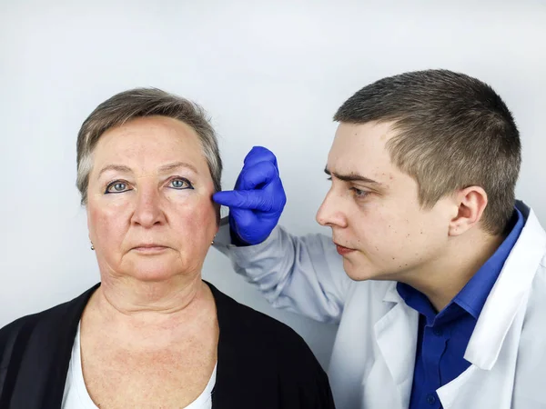 老年妇女在与整形外科医生会诊时 医生解释将实施哪些程序 模拟皱纹的外科矫正 面部整形术 — 图库照片