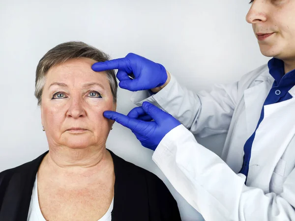 老年妇女在与整形外科医生会诊时 医生解释将实施哪些程序 模拟皱纹的外科矫正 面部整形术 — 图库照片