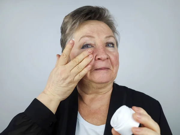 Uma Mulher Idosa Aplica Creme Facial Envelhecimento Cosmetologia Encolhimento Envelhecimento — Fotografia de Stock