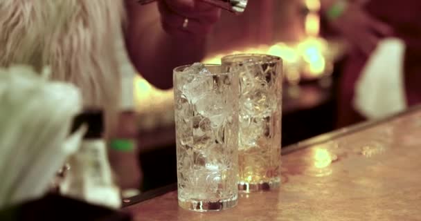Barman verse un cocktail dans un verre avec une glace à travers le métal en remuant. Processus de fabrication d'un cocktail au bar . — Video