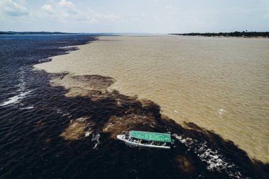 Nehirleri birbirine karıştırmak üzere olan turistlerle dolu bir tekne. Amazon.